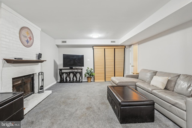 living area with carpet floors, a large fireplace, visible vents, and baseboards