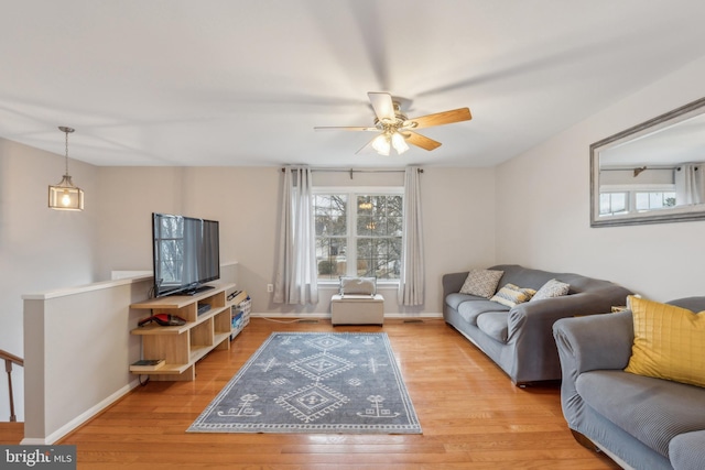 living room featuring light wood-style floors, baseboards, and a ceiling fan