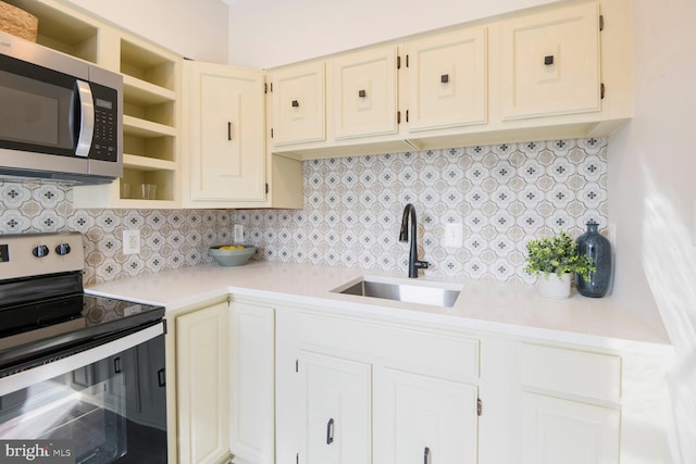 kitchen with tasteful backsplash, appliances with stainless steel finishes, light countertops, open shelves, and a sink