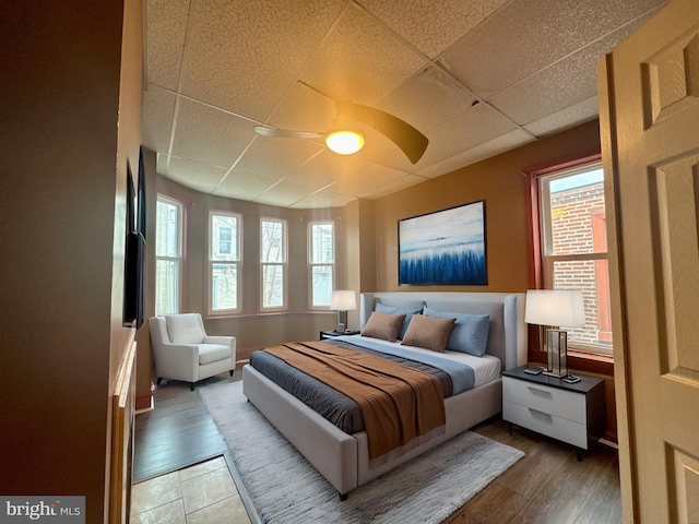 bedroom with a drop ceiling and wood finished floors