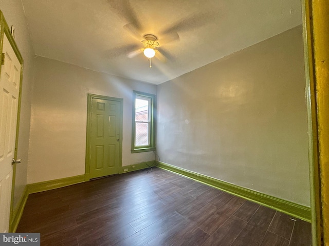 unfurnished room featuring baseboards and dark wood finished floors