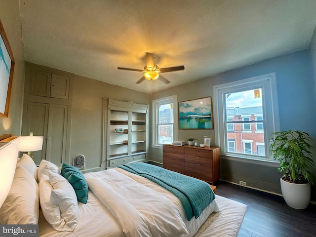 bedroom with ceiling fan, multiple windows, baseboards, and wood finished floors