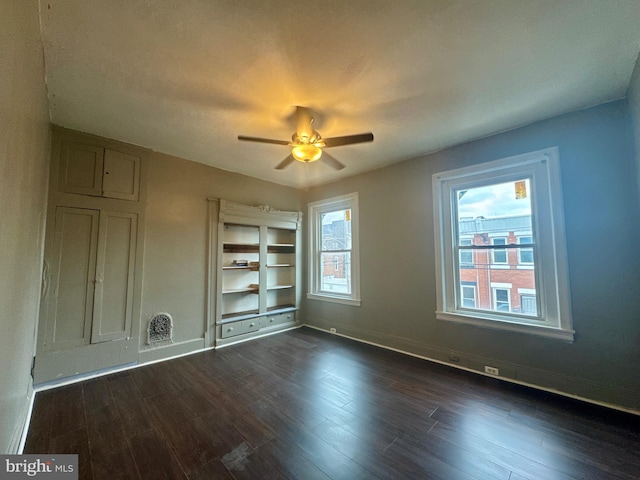 unfurnished bedroom with dark wood-style floors, multiple windows, and baseboards