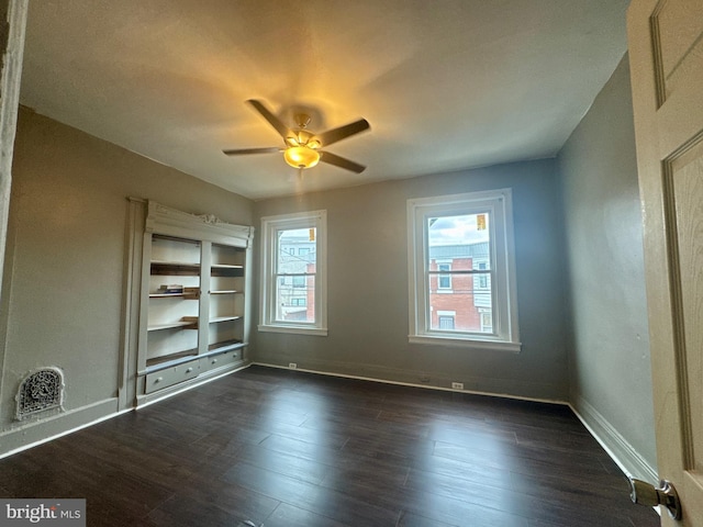 unfurnished room with baseboards, visible vents, a ceiling fan, and dark wood-type flooring