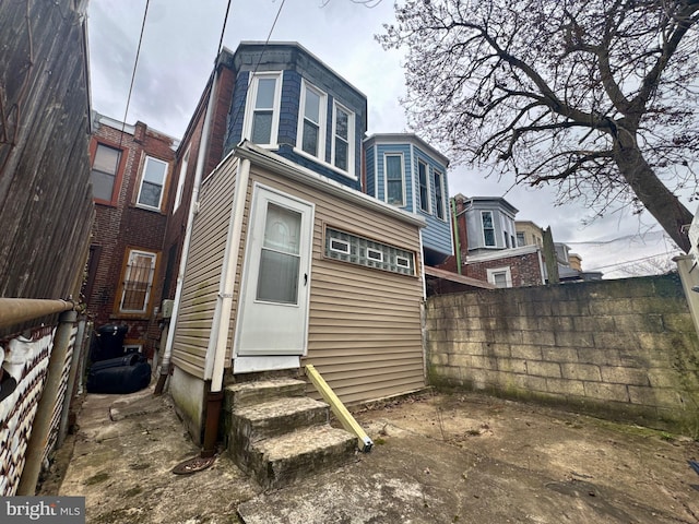 rear view of property featuring entry steps and fence