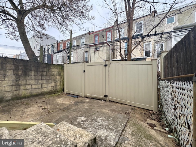 exterior space featuring a patio area, a fenced backyard, a gate, and a residential view