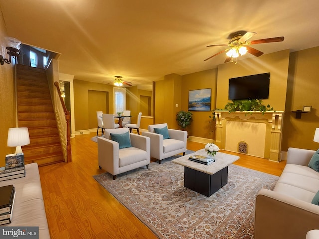 living room with ceiling fan, stairway, wood finished floors, and baseboards