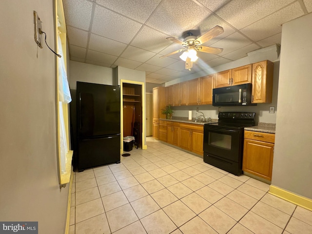 kitchen with light tile patterned floors, a drop ceiling, a ceiling fan, baseboards, and black appliances