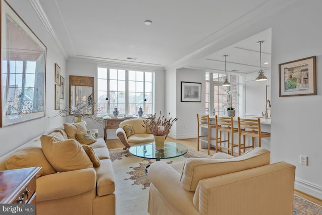 living room featuring baseboards, visible vents, ornamental molding, and wood finished floors