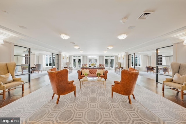 living area featuring visible vents, a wall of windows, wood finished floors, and french doors