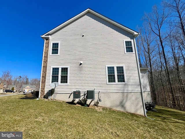 view of home's exterior featuring central air condition unit, brick siding, and a yard