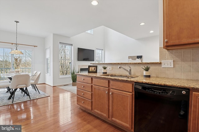 kitchen with dishwasher, light stone counters, a peninsula, light wood-type flooring, and a sink