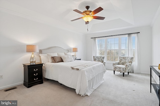 bedroom with ornamental molding, a tray ceiling, visible vents, and light colored carpet