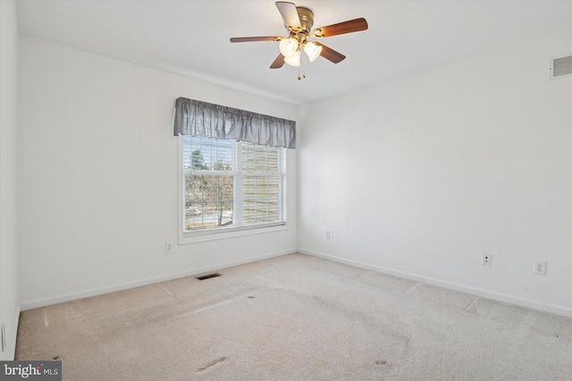 carpeted empty room with baseboards, visible vents, and ceiling fan