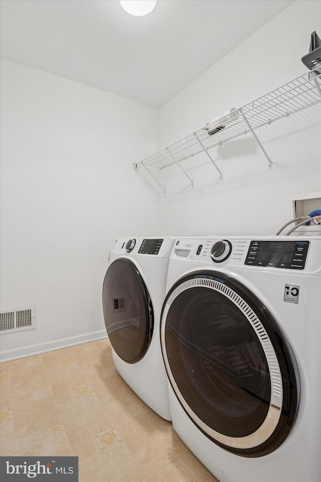 laundry area with laundry area, baseboards, visible vents, and washing machine and clothes dryer