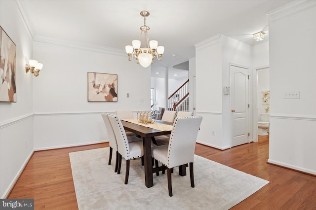 dining area featuring baseboards, ornamental molding, a chandelier, and wood finished floors