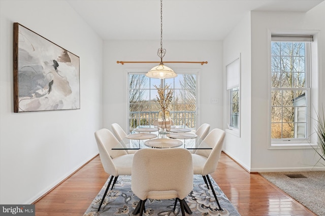 dining room with visible vents, baseboards, and hardwood / wood-style flooring