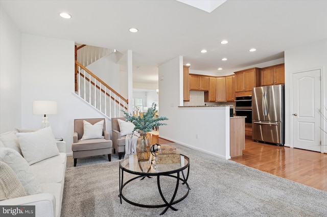 living room featuring light carpet, a skylight, stairs, light wood-type flooring, and recessed lighting