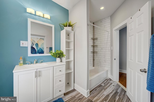 bathroom featuring washtub / shower combination, wood finished floors, vanity, and baseboards