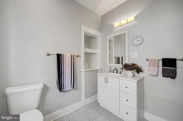 bathroom featuring baseboards, vanity, and toilet