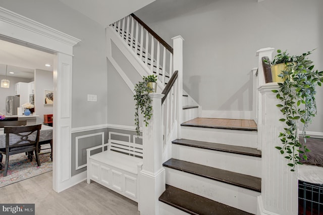 stairs featuring recessed lighting, wood finished floors, and a decorative wall