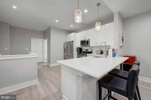 kitchen with tasteful backsplash, appliances with stainless steel finishes, light countertops, light wood-type flooring, and a sink