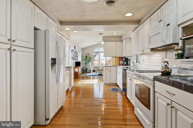 kitchen featuring visible vents, light wood-style floors, white cabinetry, vaulted ceiling, and white appliances