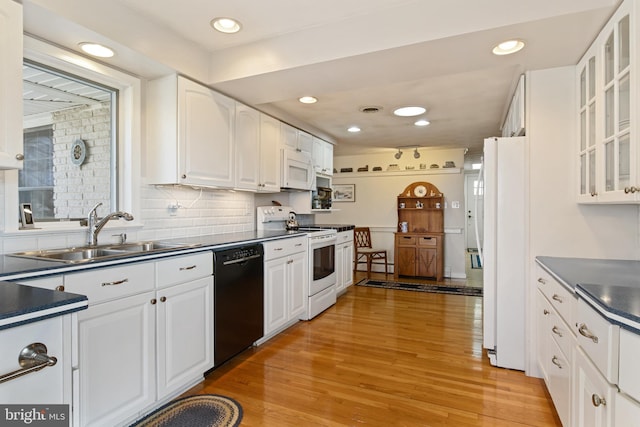 kitchen with white appliances, dark countertops, light wood-type flooring, white cabinetry, and a sink