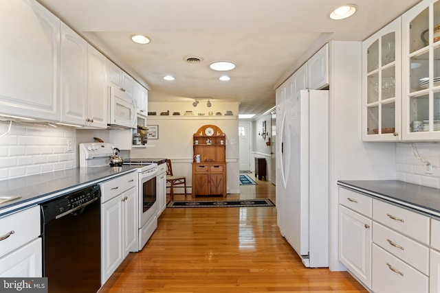 kitchen with dark countertops, white appliances, light wood-style flooring, and visible vents