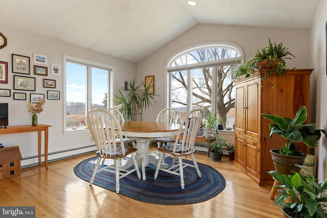 dining area featuring light wood finished floors, a baseboard radiator, plenty of natural light, and vaulted ceiling