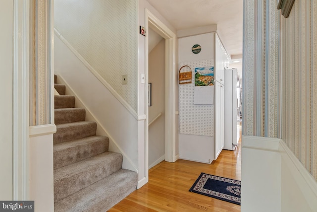 stairway featuring wallpapered walls and wood finished floors