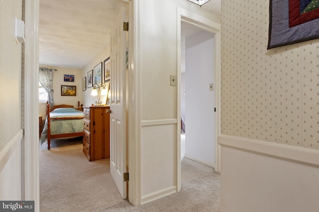 hallway with light carpet, wallpapered walls, and baseboards