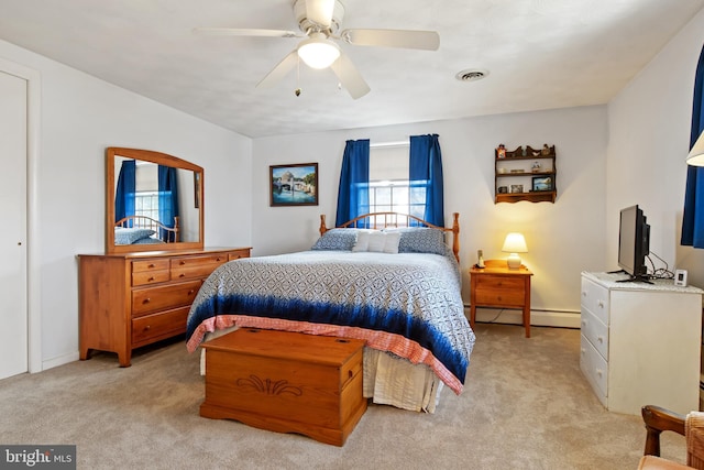 bedroom featuring a ceiling fan, baseboard heating, visible vents, and light colored carpet