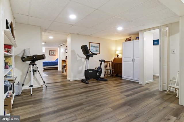 workout room with a paneled ceiling, baseboards, wood finished floors, and recessed lighting