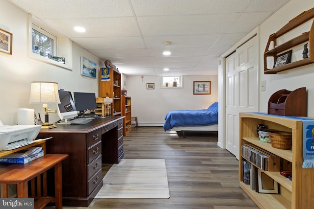 bedroom with a paneled ceiling, a baseboard radiator, recessed lighting, and wood finished floors