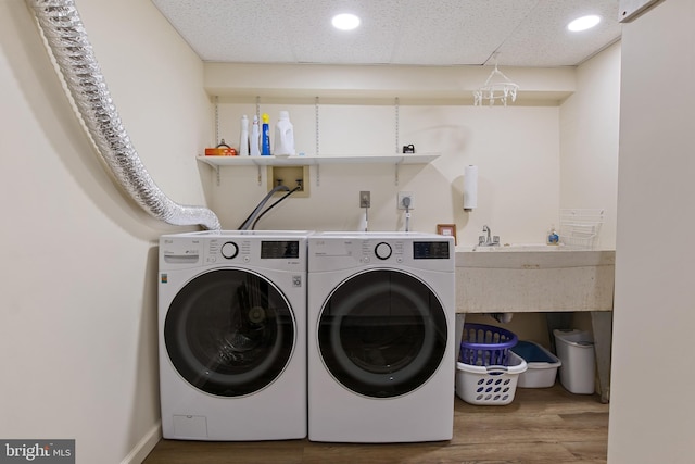 laundry room with laundry area, baseboards, wood finished floors, and washing machine and clothes dryer