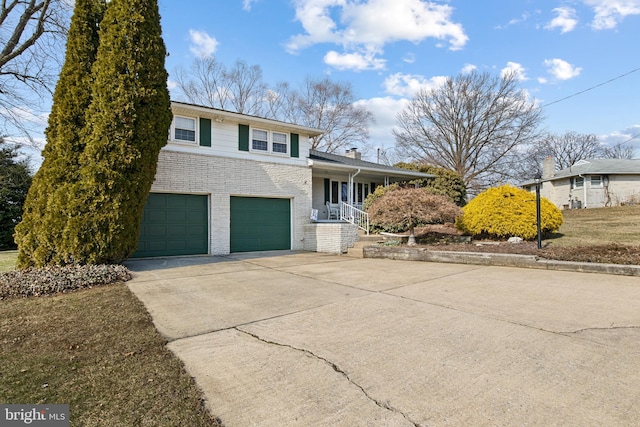 tri-level home with brick siding, a chimney, a porch, a garage, and driveway