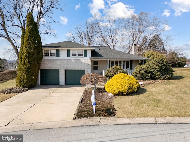 tri-level home with brick siding, a chimney, an attached garage, a front yard, and driveway