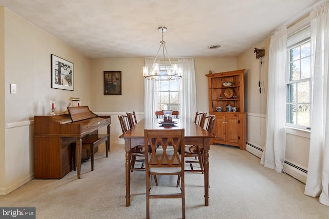 dining space with a chandelier, a healthy amount of sunlight, light carpet, and baseboard heating