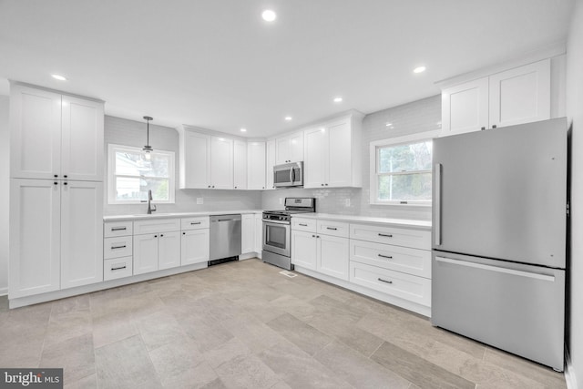 kitchen with backsplash, stainless steel appliances, light countertops, white cabinetry, and a sink