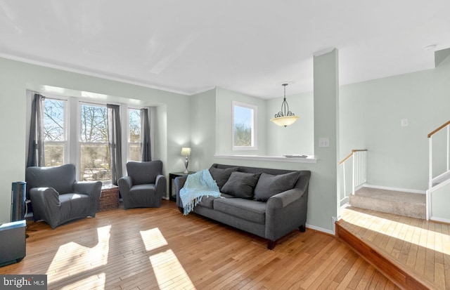 living room featuring light wood-type flooring, plenty of natural light, stairs, and baseboards