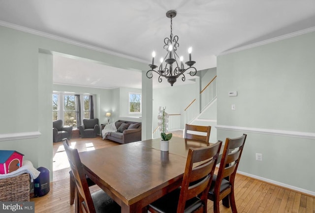 dining room featuring light wood-type flooring, crown molding, stairway, and baseboards