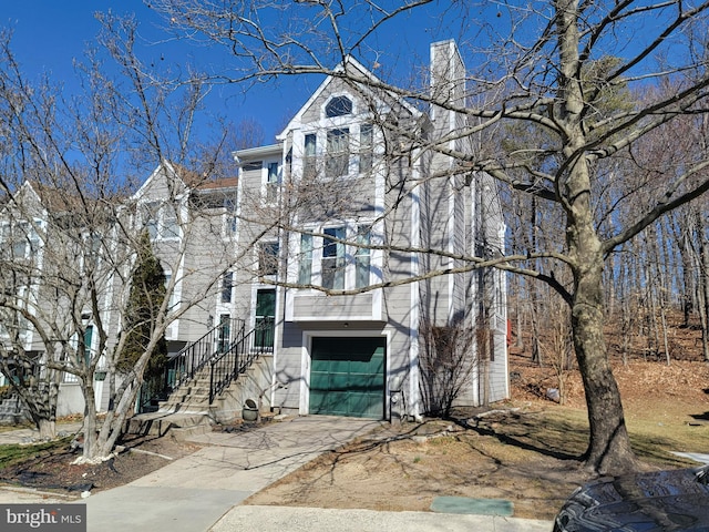 view of side of property featuring a garage, concrete driveway, and a chimney