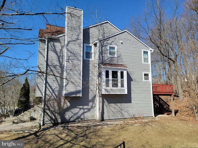 back of house with stairs, a chimney, and a deck