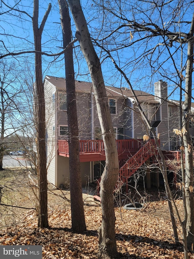 back of property with a chimney, stairway, and a wooden deck