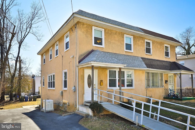 townhome / multi-family property featuring roof with shingles, fence, and stucco siding