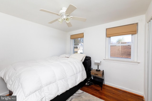 bedroom with dark wood finished floors, a ceiling fan, and baseboards