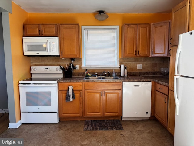 kitchen featuring dark countertops, decorative backsplash, brown cabinets, white appliances, and a sink