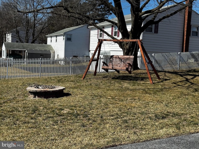 view of jungle gym with a fire pit, a lawn, and fence