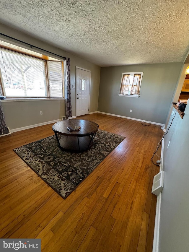 foyer entrance featuring baseboards, wood-type flooring, and a textured ceiling